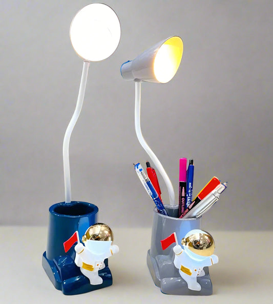 Desk lamp with astronaut design holding pens on a desk. Astronaut LED Desk Lamp with Penholder - Madina Gift