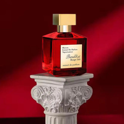 Red Barakkat Rouge 540 perfume bottle with gold cap on a decorative white column against a red background