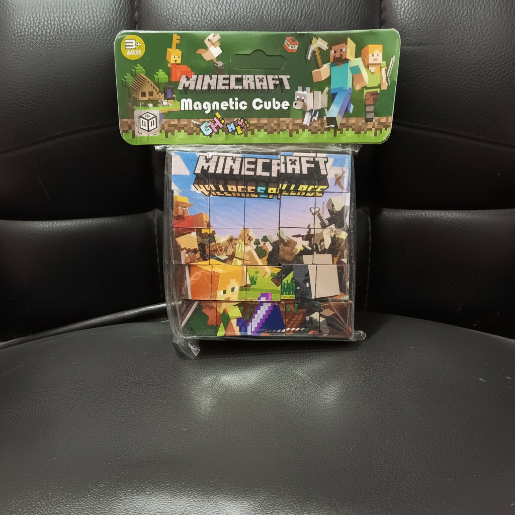 A packaged Minecraft Magnetic Cube toy set in clear plastic packaging, resting on a black leather surface. The top card is green with Minecraft branding and character graphics, and the bottom package shows colorful magnetic cube pieces.