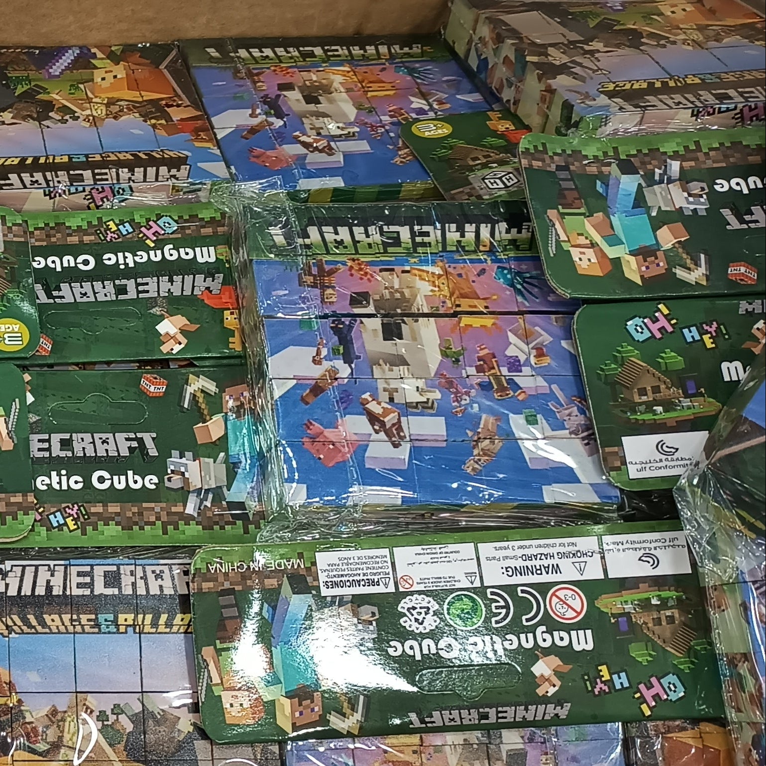 A bulk display of Minecraft Mega Build cube toy sets in their original green packaging, stacked inside a cardboard box.